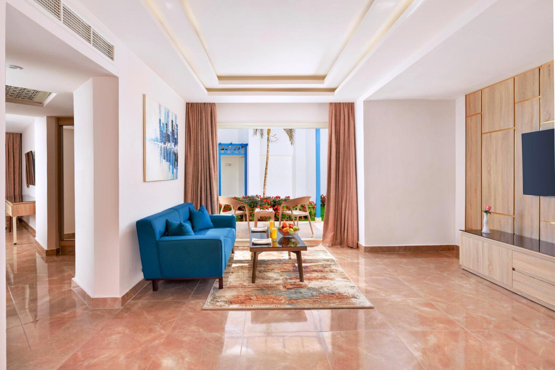 Pickalbatros Palace Sharm - "Aqua Park" Exterior foto The photo shows a modern living room decorated with a bright and inviting style. In the center, there is a cozy blue sofa positioned against a wall. A coffee table sits in front of the sofa, accompanied by a decorative rug underneath. The room featur